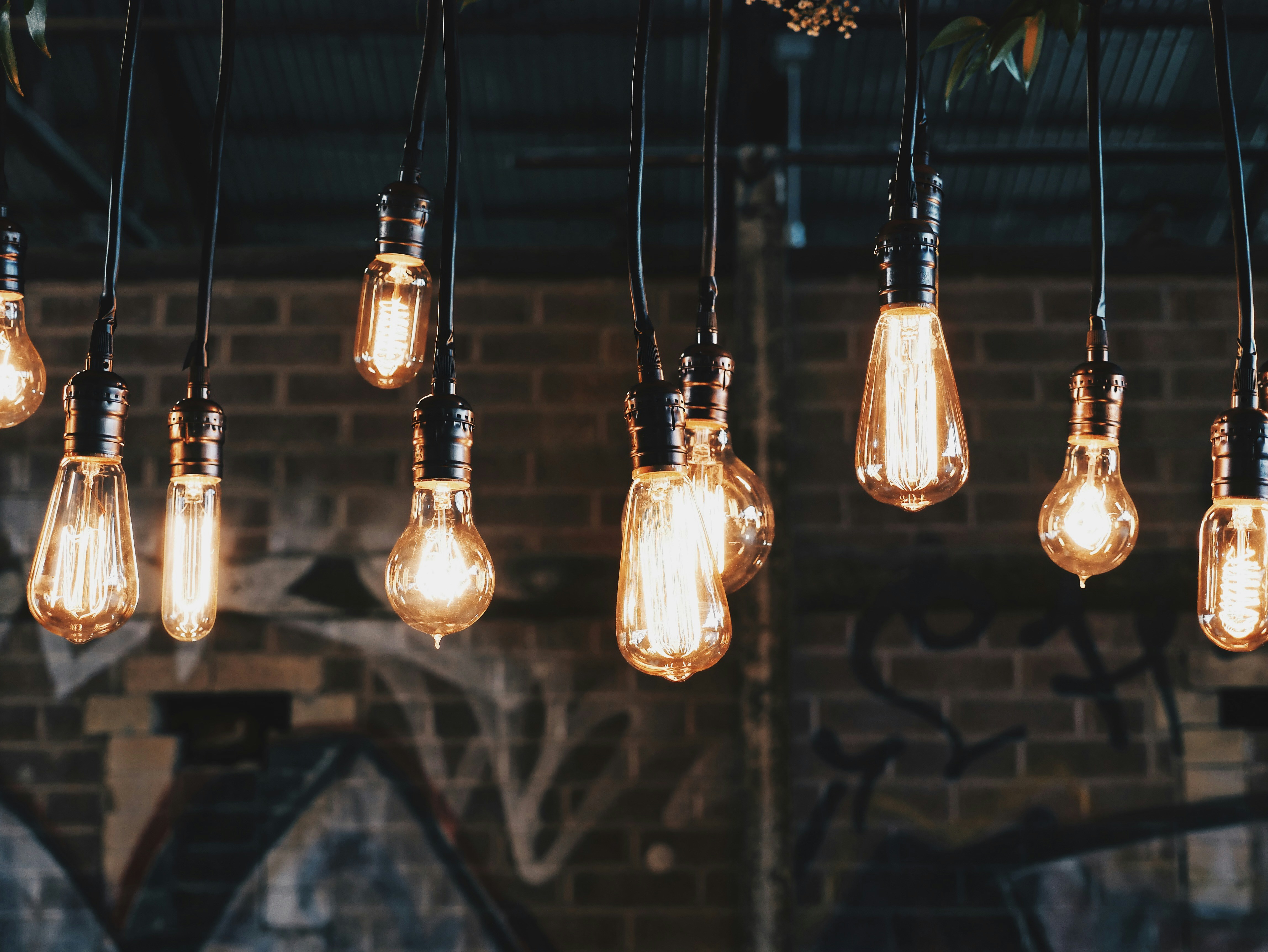 Edison bulbs glowing against an industrial brick and graffiti wall