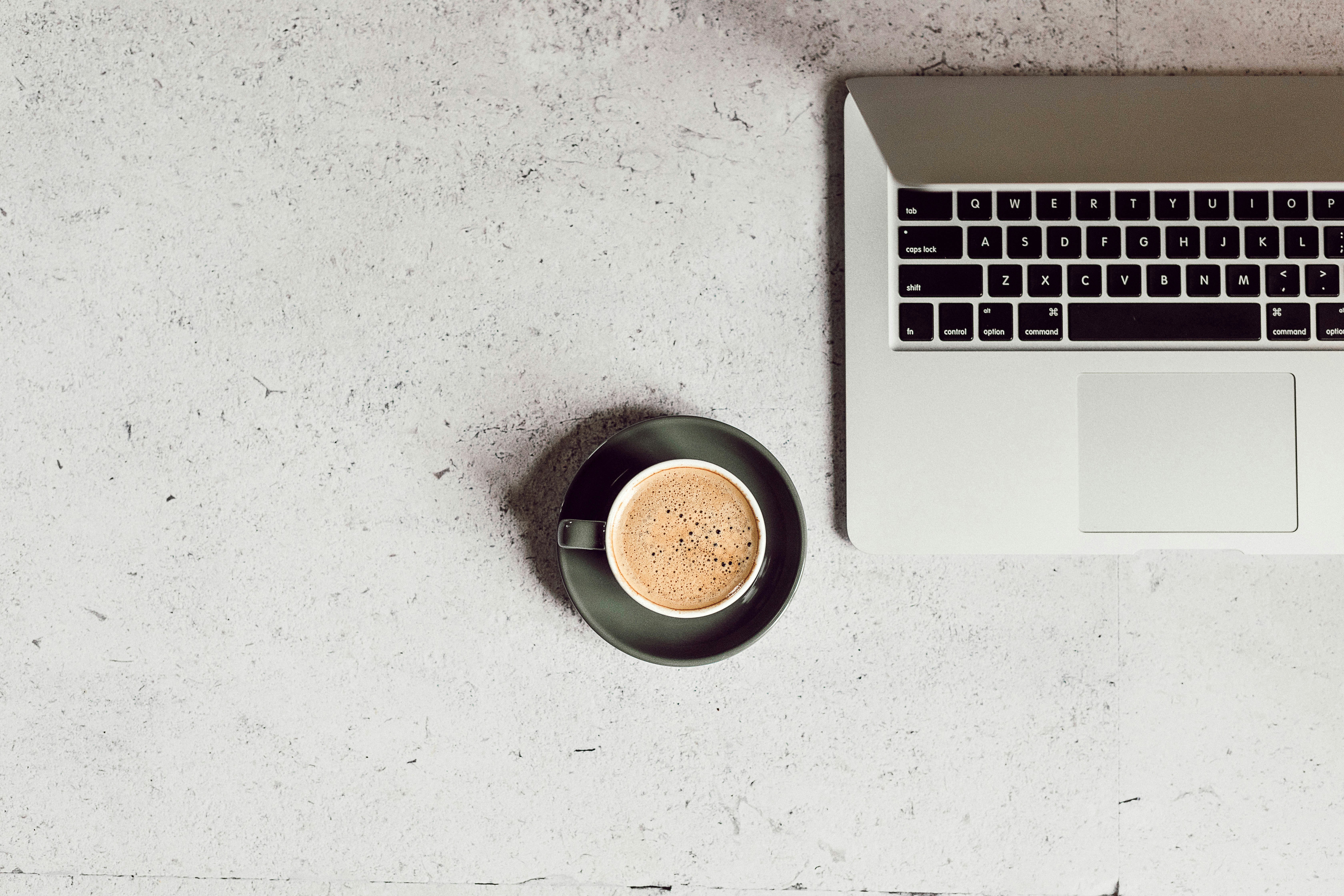 Flatlay of MacBook and espresso on a concrete desk