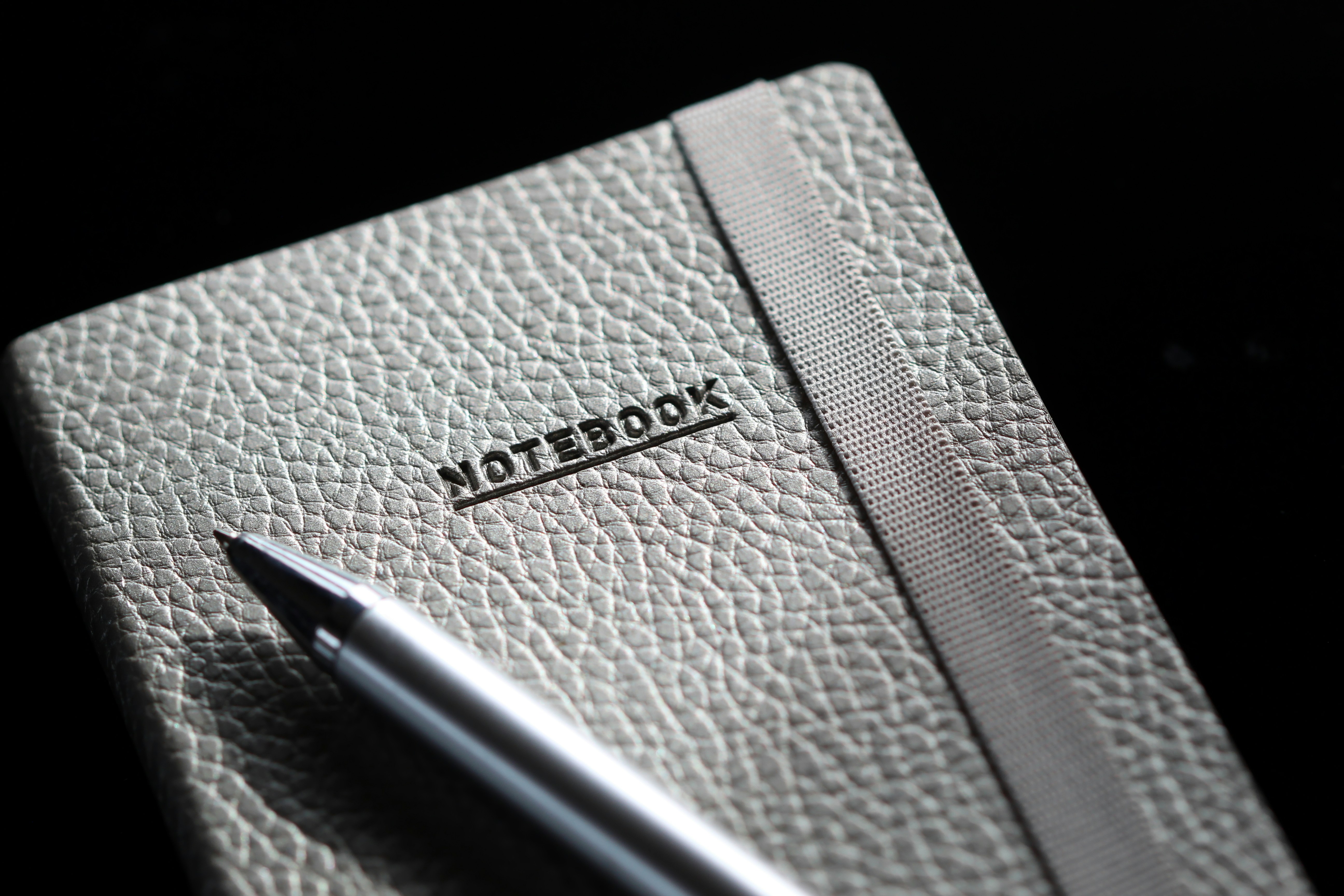 Grey leather notebook with silver pen close up