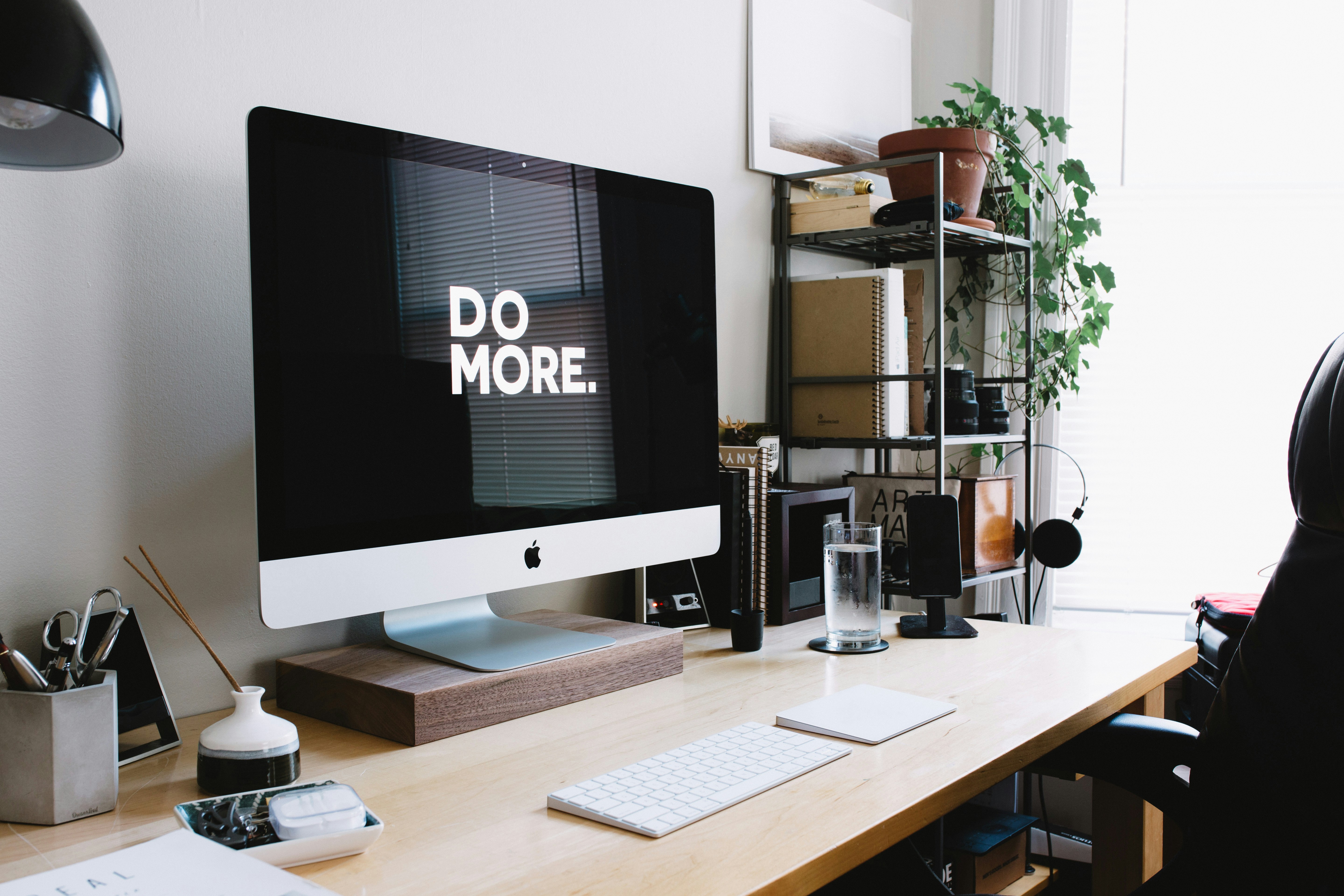 Minimalist iMac desk setup with 'Do More' wallpaper